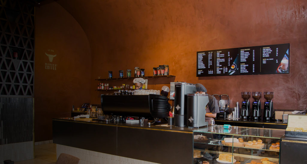 Cafe counter with digital menu boards above the coffee station