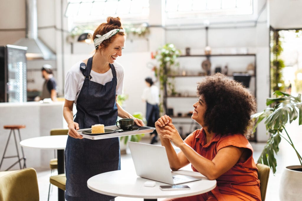 Waiter serving a customer in a cafe with background music playing