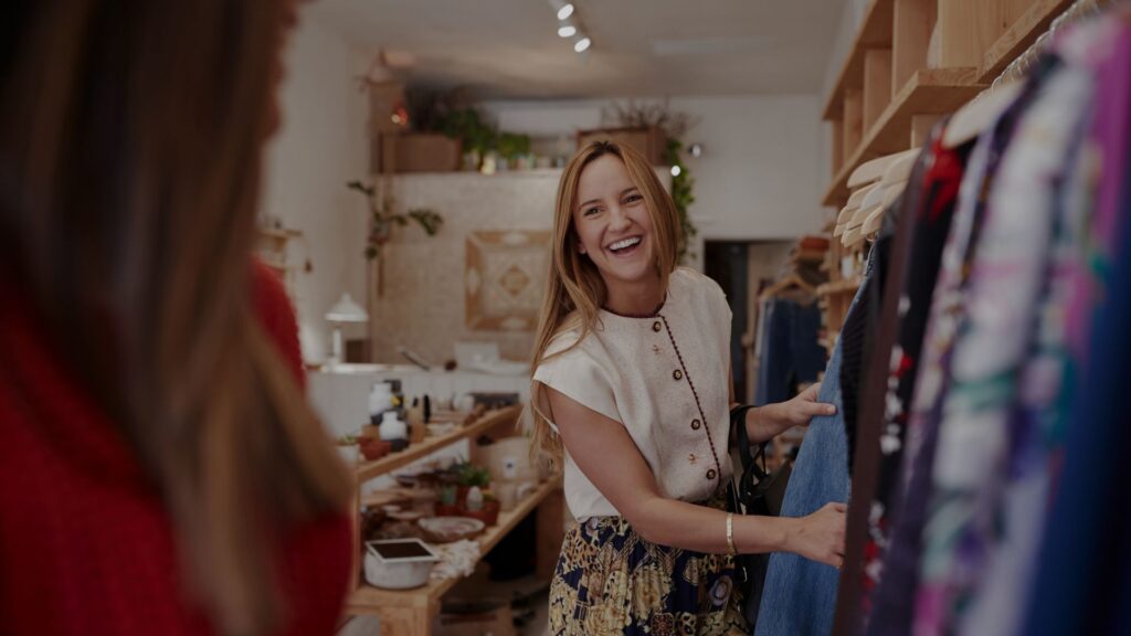 Smiling shopper browsing clothing in a store with background music playing