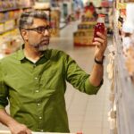 Middle-aged man shopping and choosing the best product based on the on digital shelf display.