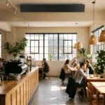 Coffee shop interior with customers at tables and a ceiling-mounted speaker playing background music